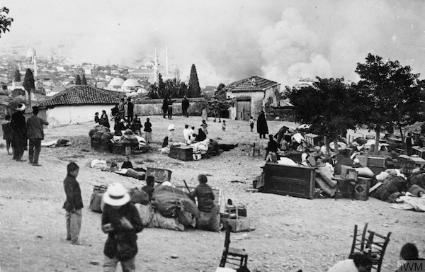 Photograph: The great fire in Salonika town, 18-21 August 1917: refugees with their salvaged possessions observe the blaze from a place of safety. © IWM HU 58890