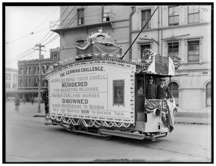 Tram decorated with World War 1 propaganda, including unidentified tram conductor and passenger, Temperance and General Life Assurance Society building in background, Cathedral Square, Christchurch